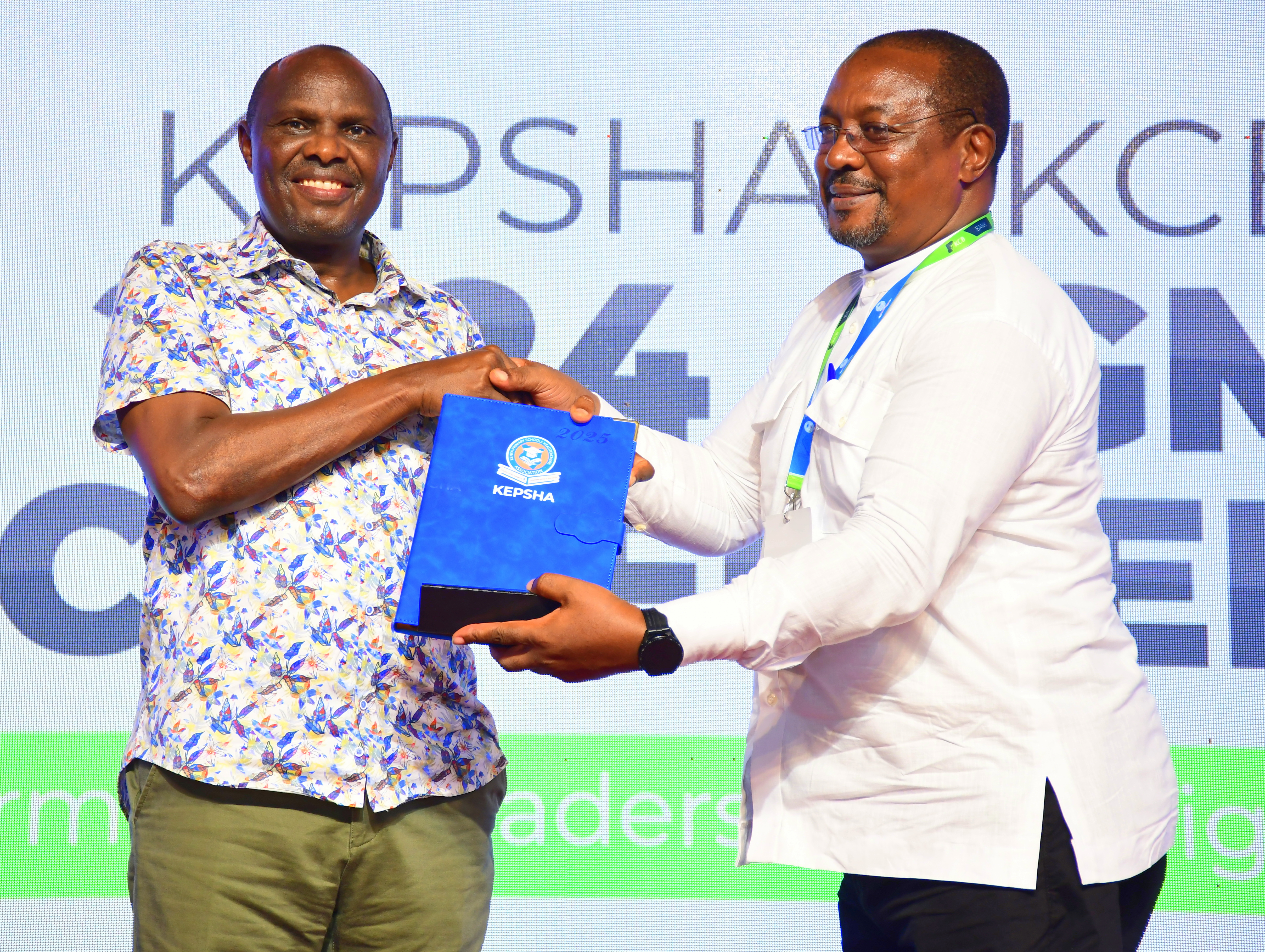 Chief of Staff and Head of Public Service Felix Koskei (L) receives memorabilia from chairperson of the Kenya Primary School Heads Association (KEPSHA) chairperson Johnson Nzioka during the opening session of the 25th annual general meeting and conference, Mombasa