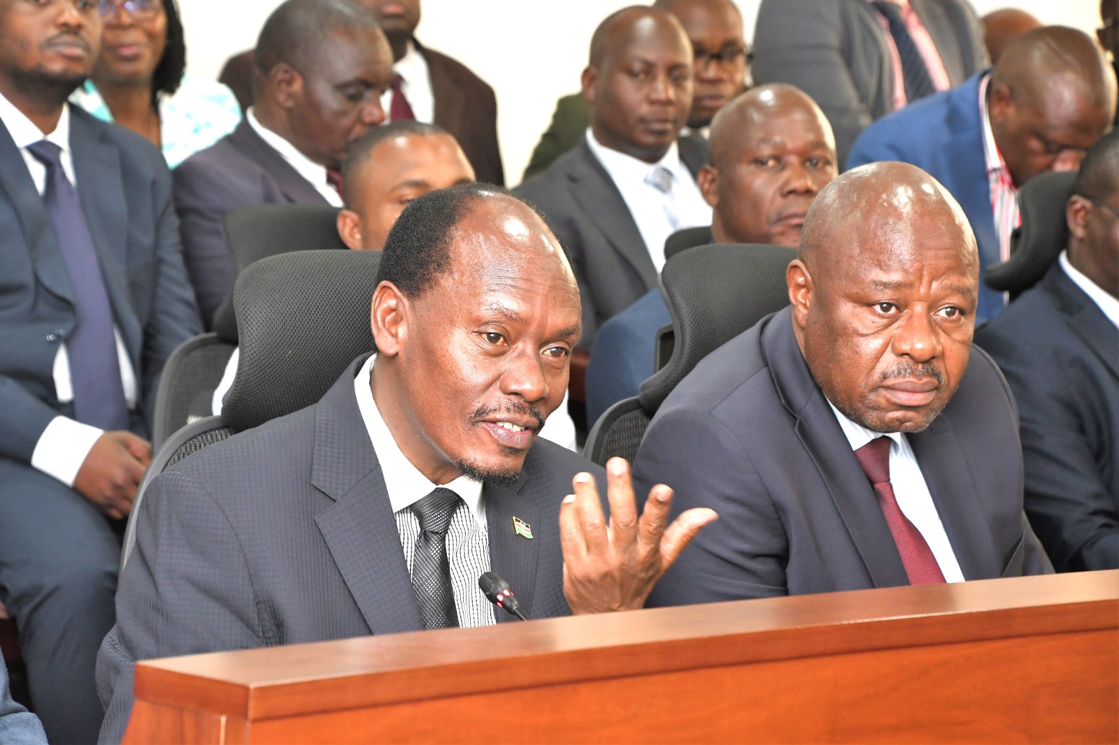 Outgoing Principal Secretary for Broadcasting and Telecommunications Prof Edward Kisiangáni (left) with MICDE CS William Kabogo (centre) when they appeatred before the Senate Committee in Parliament. 