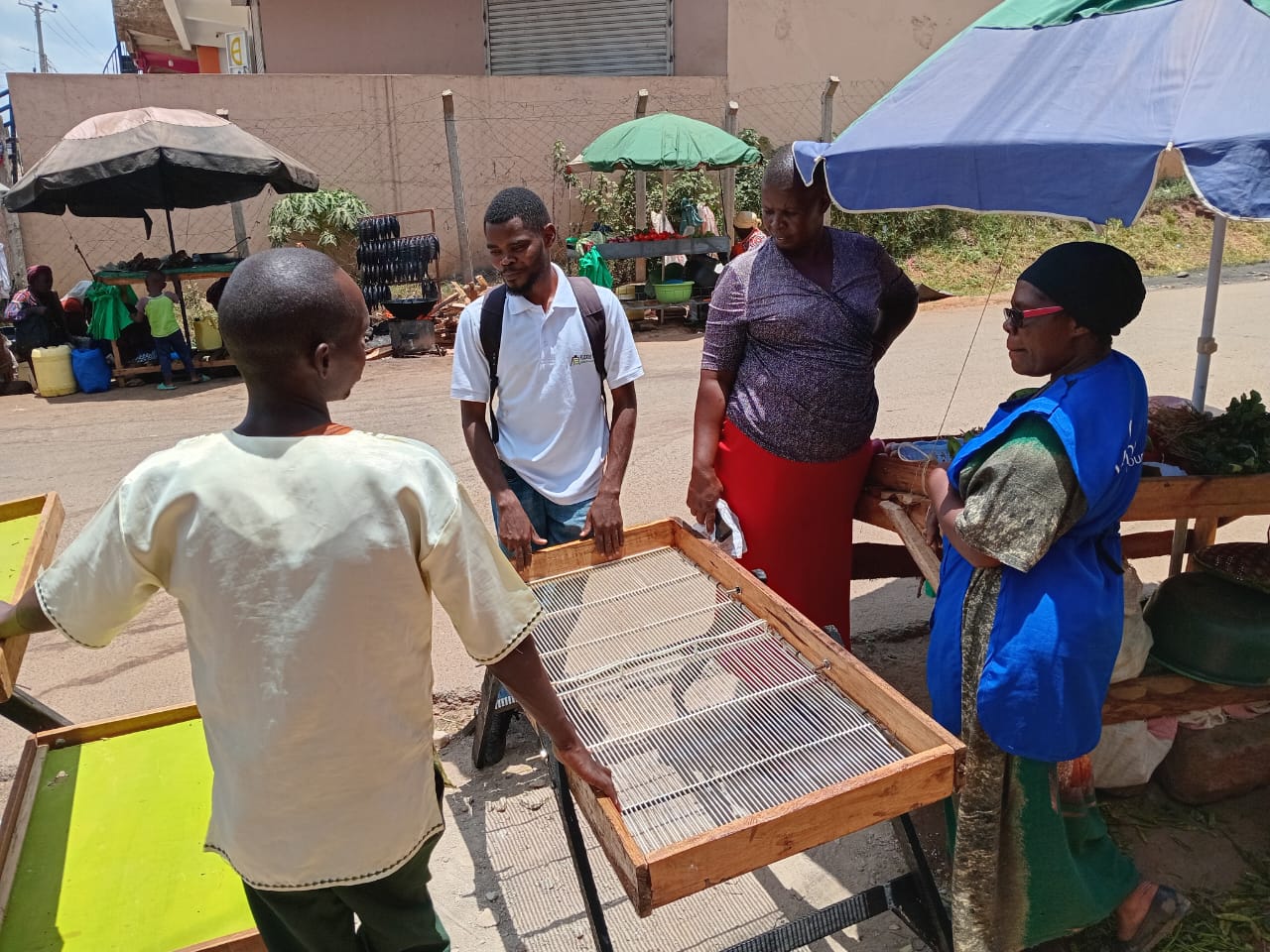 A mechanical engineering student at Masinde Muliro University of Science and Technology (MMUST) Kaguru Njoroge Muchina (Centre) displays and markets his flexi stall to grocery vendors in Kakamega town. Photo by Gloria Asacha