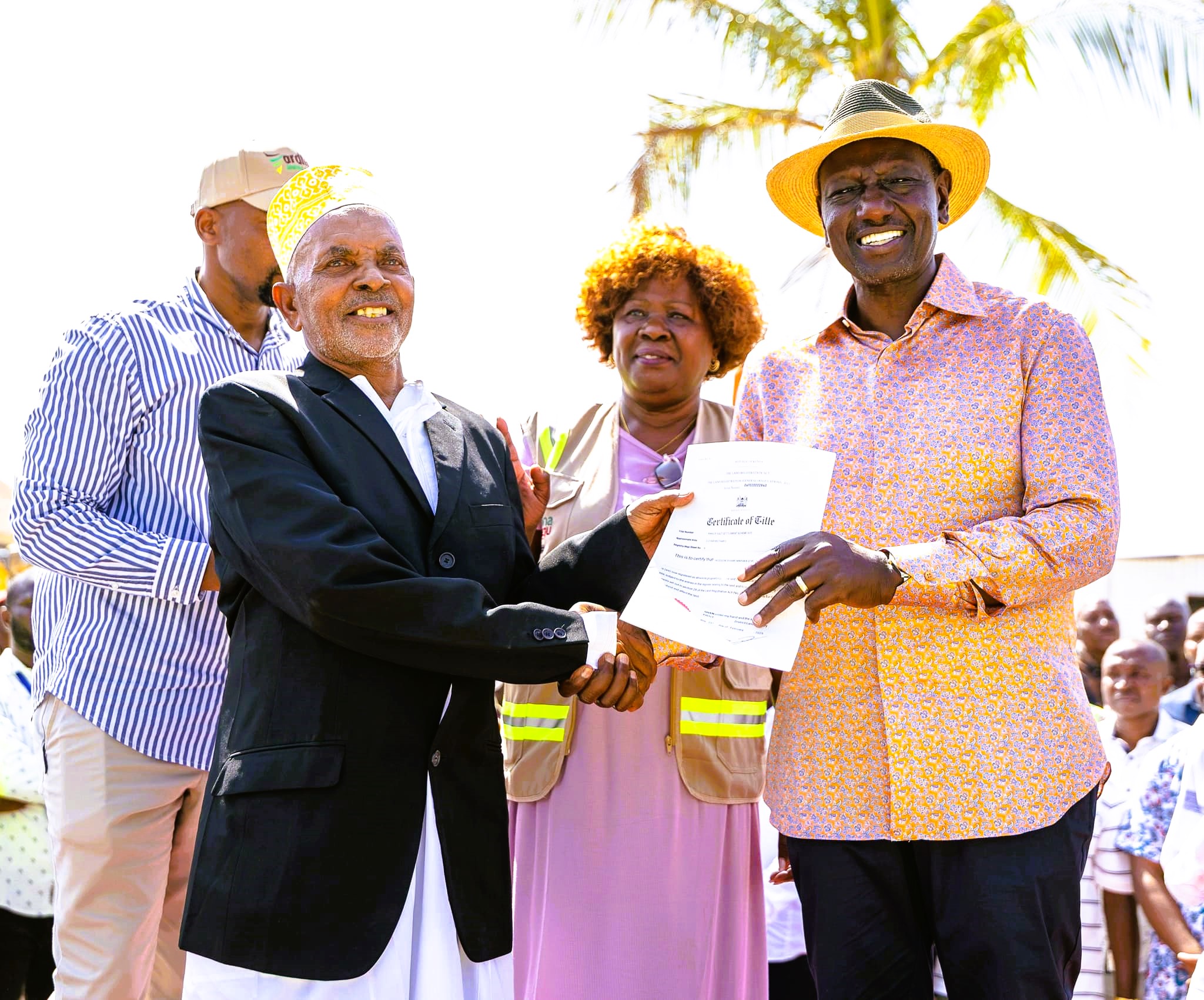 A Kwale resident receives a title deed from President  William Ruto. Looking on is Lands Cabinet Secretary Alice  Wahome. 