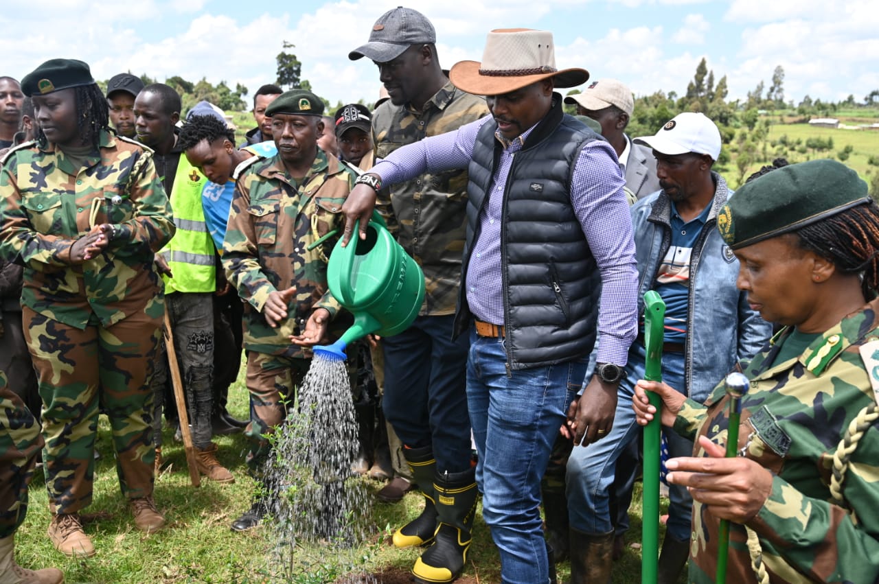 The Principal Secretary for State Department for Environment and Climate Change, Dr. Eng. Festus Ng’eno (centre) waters a tree during a planting exercise in Kuresoi, Nakuru County.