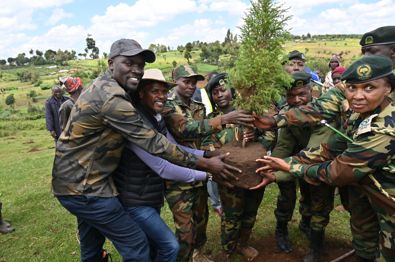 The Principal Secretary for State Department for Environment and Climate Change, Dr. Eng. Festus Ng’eno (centre) waters a tree during a planting exercise in Kuresoi, Nakuru County.
