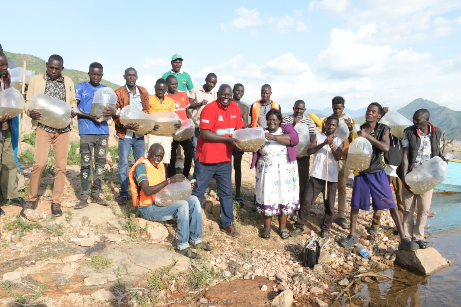 Ann Mokoro, the regional director for five counties in the North Rift region including West Pokot,Trans Nzoia, Elgeyo Marakwet, Turkana, and Uasin Gishu, (Left) leads the restocking of Turkwel dam with 80,000 fingerlings donated by national government in an efforts aim to sustain the fishery as a vital source of livelihood. Photo By Anthony Melly