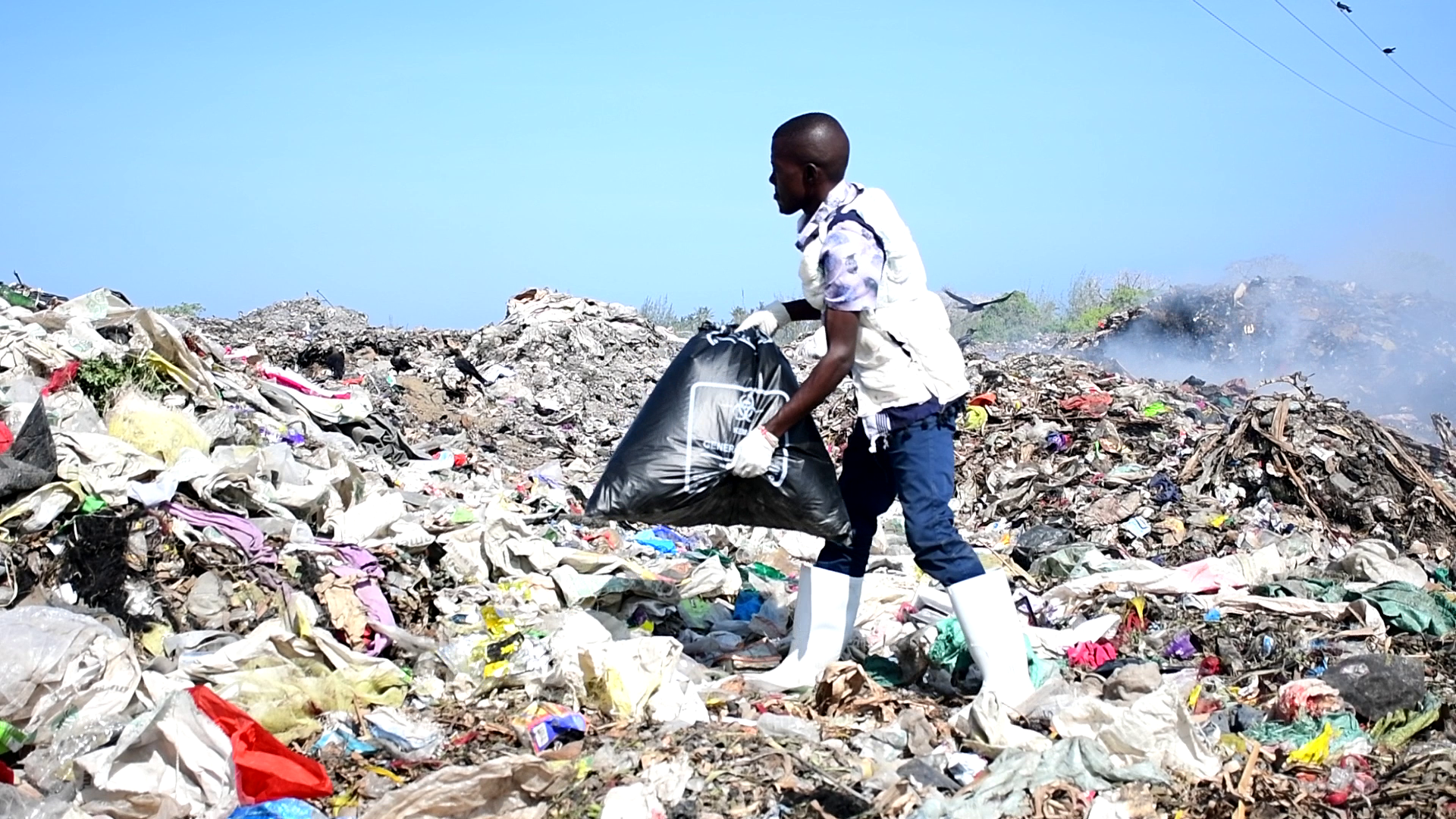 Public Health Officer alias Diaperman dropping a special diaper storage bag containing used diapers at major dumping site at Matsangoni in Kilifi. 