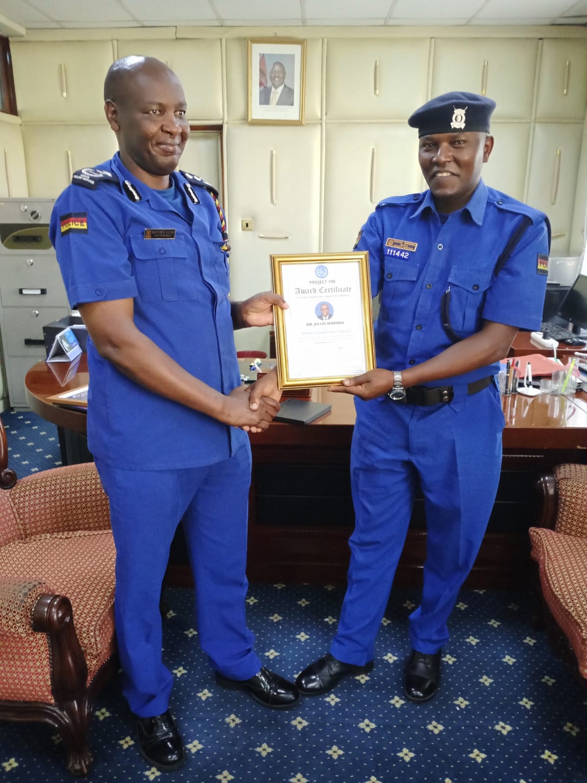 Julius Mwenda at the Police Headquarters in Nairobi as he receives some of the awards from Principal Assistant to the Inspector General Mathew Kutoh. Photo/Anne Kangero