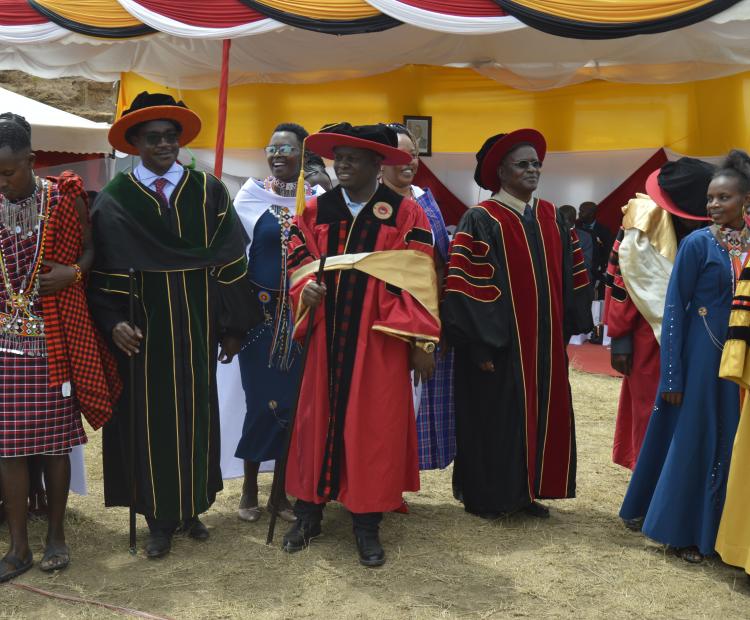 Education Cabinet Secretary Julius Migos Ogamba (in spectacles) and Narok County Deputy Governor Tamalinye Koech (in red gown) during the first graduation of the Maasai Mara Technical Voluntary Education and Training (TVET) join Maasai dancers for a jig