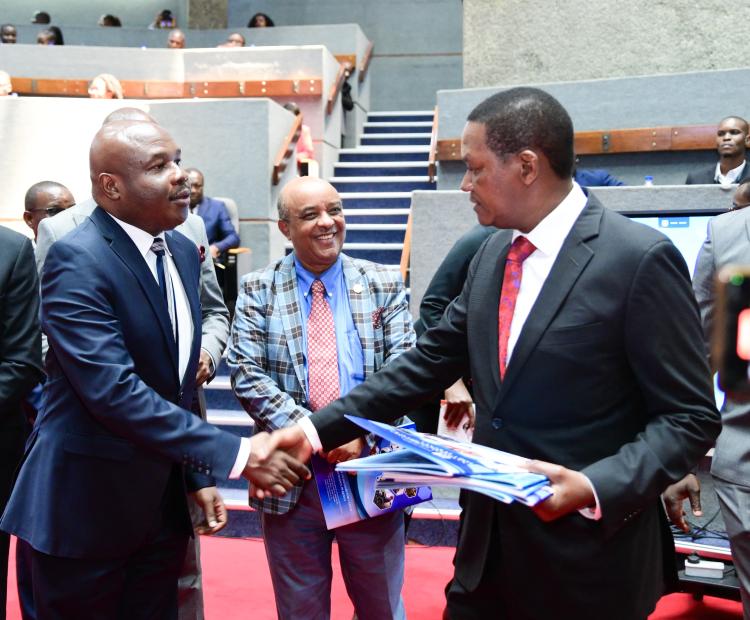 Labour Cabinet Secretary Dr. Alfred Mutua hands over policy framework documents to the Prinicipal Secretary State Department for Labour, Mr.Shadrack Mwadime (lefT) launched during the East African Employability summit. Looking on (centre) Dr.Meshesha Shewaraga,representing the African Union Commission