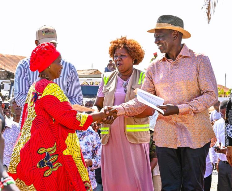 A Kwale resident receives a title deed from President  William Ruto. Looking on is Lands Cabinet Secretary Alice  Wahome. 