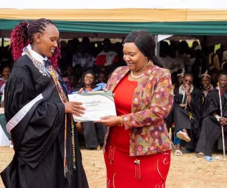 Cabinet Secretary for Tourism and Wildlife Rebecca Miano issues a certificate to a student from Wildlife Tourism College of Maasai Mara.
