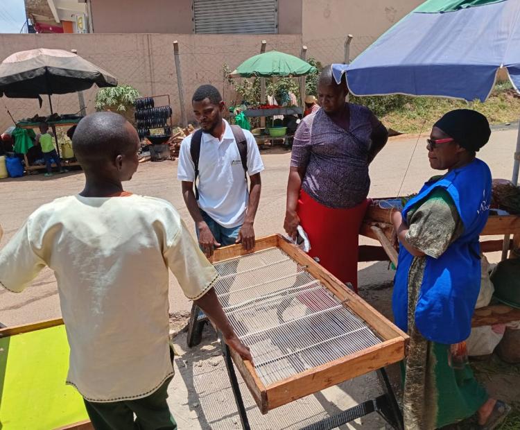 A mechanical engineering student at Masinde Muliro University of Science and Technology (MMUST) Kaguru Njoroge Muchina (Centre) displays and markets his flexi stall to grocery vendors in Kakamega town. Photo by Gloria Asacha