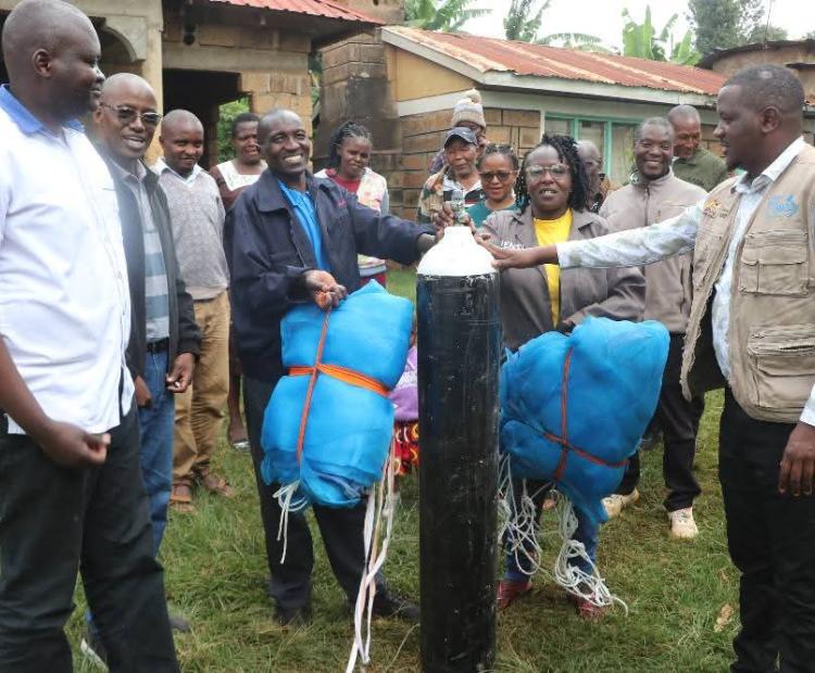 Tharaka Nithi County Fisheries Chief Officer Antony Kiruja issues an oxygen cylinder to farmers' at Kamwimbi. Photo/Dickson Mwiti)